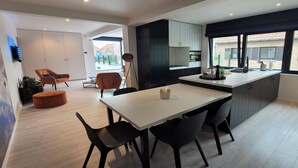 A modern kitchen with a central island, black chairs, and a white dining table.