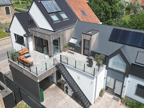 Ein modernes, zweistöckiges Haus mit Balkon, Treppe und Solaranlage.