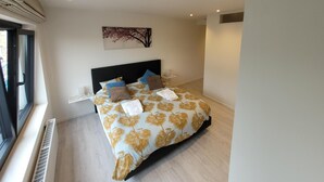 A modern bedroom with a large bed, a window, and a ceiling with recessed lighting.