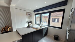 A modern kitchen with a large window, dark cabinetry, and a white countertop.