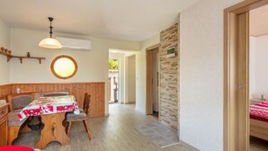 A dining area with a wooden table and chairs, a round window, and a hallway leading to another room. - Ideal Holiday Home in Wutha-Farnroda near City Center (Wutha-Farnroda)
