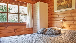 A wooden cabin room with a bed, a window with curtains, a white cabinet, and a framed picture on the wall. - 6 Person Holiday Home in Hurup Thy (Hurup Thy)