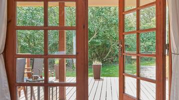 Een houten deur met glaspanelen die uitkomt op een terras met uitzicht op een tuin.