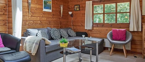 L'intérieur d'un chalet accueillant, avec un canapé, un fauteuil et une petite table agrémentée d'une plante.