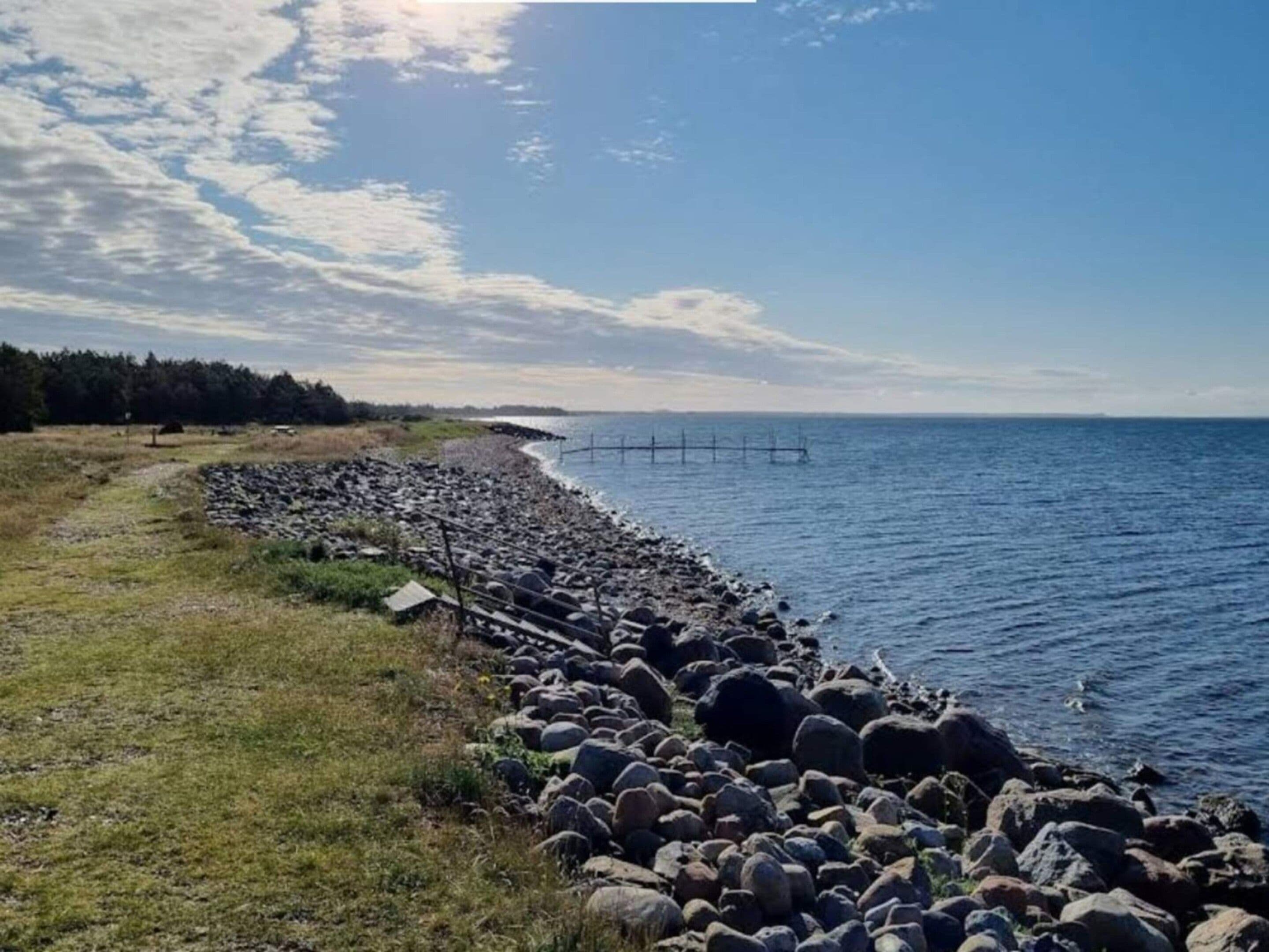 Une côte rocheuse offrant une vue dégagée sur la mer et sur une terre lointaine.
