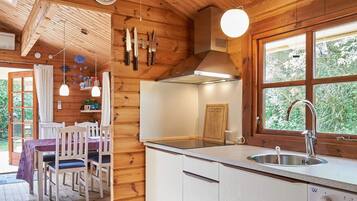 A wooden interior with a kitchen area, dining table, and chairs.