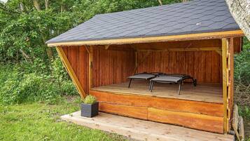 A wooden structure with a sloped roof, a platform, and two chairs.
