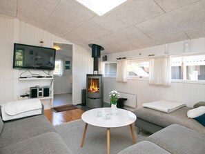 A modern living room with a fireplace, grey sofas, a flat-screen TV, and a round coffee table. - 8 Person Holiday Home in Blokhus (Blokhus)