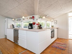 A spacious kitchen with a large island, white cabinetry, and a tiled floor.