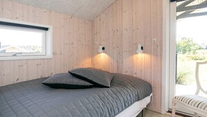A bedroom with a bed, a window, and a chair.