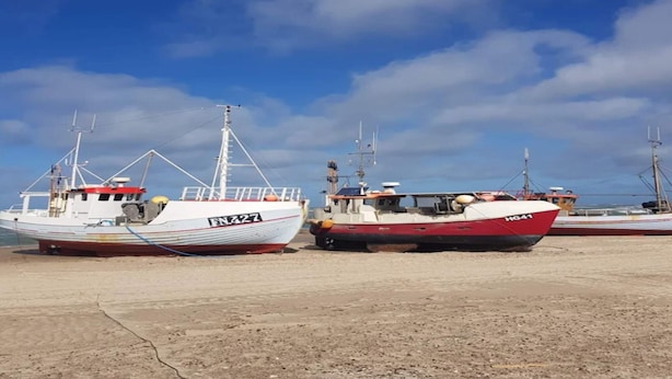 Two boats docked at a marina with a clear sky.