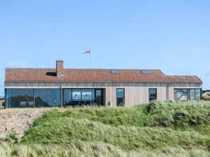 A modern house with a flat roof, large windows, and a flag on top. - Holiday Home in Blokhus (Blokhus)
