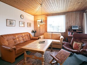 A cozy living room with a wooden ceiling, a brown leather sofa, a wooden coffee table, and a television on a wooden stand. - 4 Person Holiday Home in Millinge (Millinge)