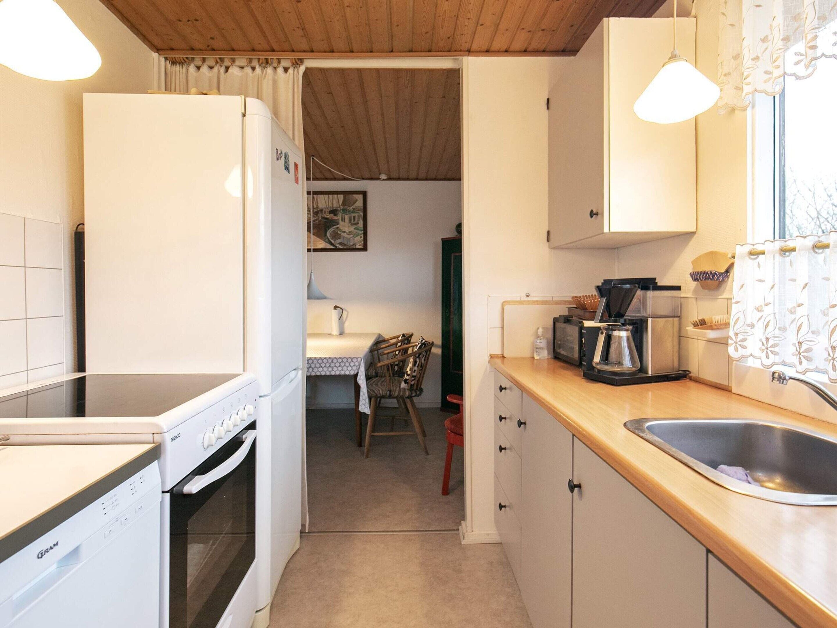 A compact kitchen with a dishwasher, a coffee maker, and a sink.