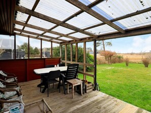 A covered outdoor dining area with a table and chairs, a view of the surrounding landscape, and a wooden floor. - 4 Person Holiday Home in Millinge (Millinge)