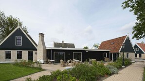 A traditional building with a black facade, a chimney, and a covered patio area with outdoor seating. - Chalet in Wiringherlant With Garden Terrace (Hippolytushoef)