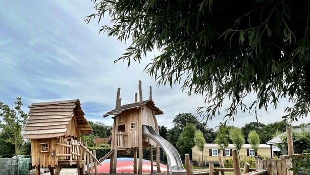 A wooden play structure with a slide and a small house. - Chalet in Wiringherlant With Garden Terrace (Hippolytushoef)