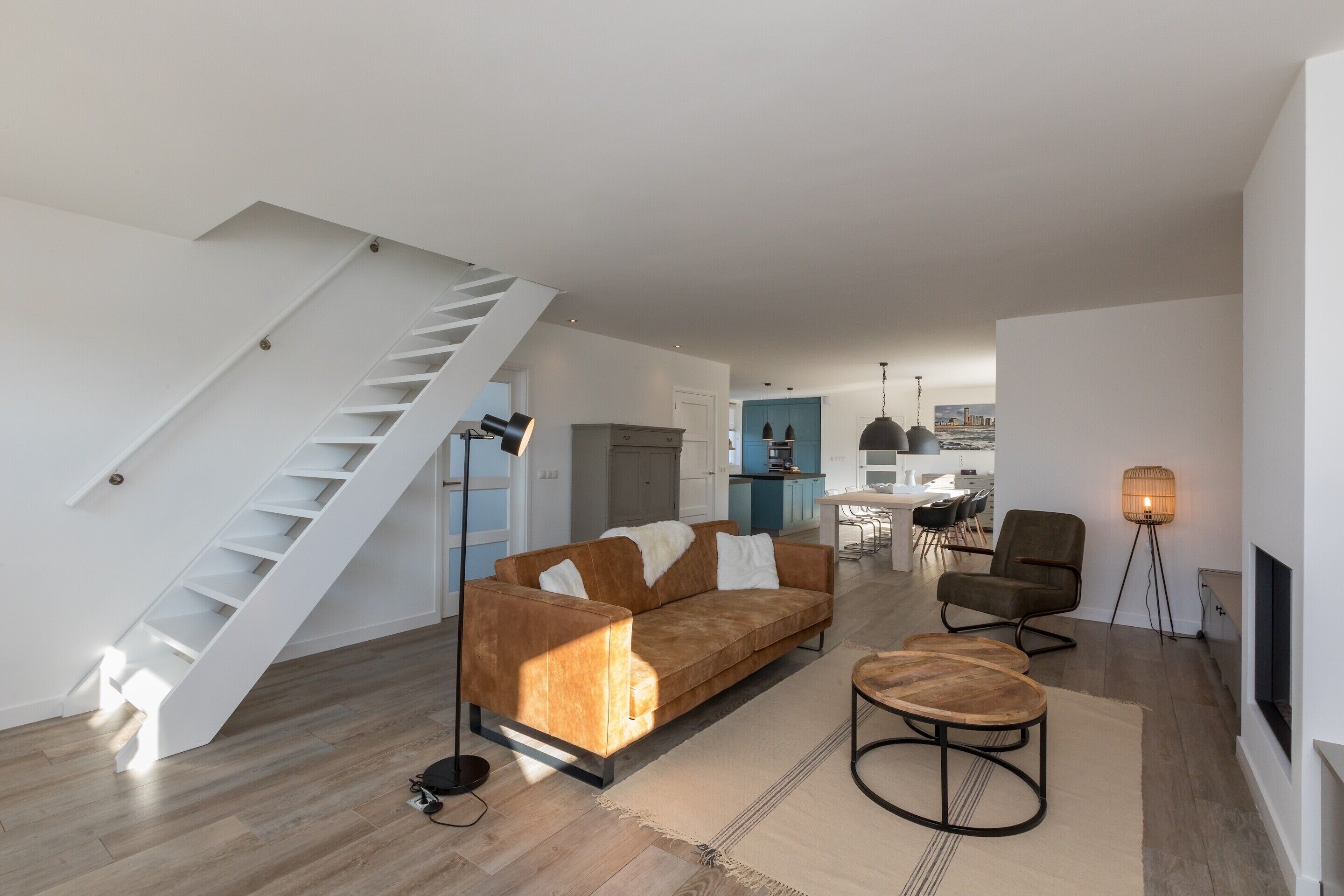 Un salon moderne avec un escalier, un canapé, une table basse et un téléviseur.