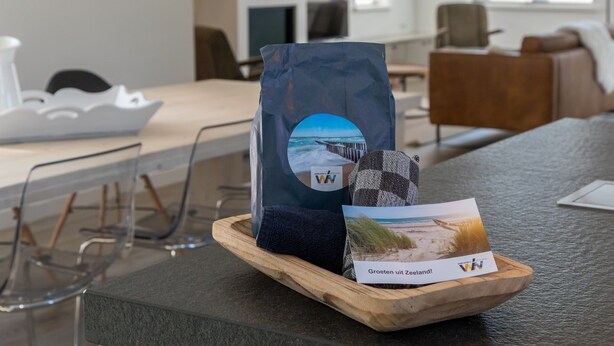 Un vassoio di legno con una card a tema spiaggia e una borsa su una superficie strutturata.