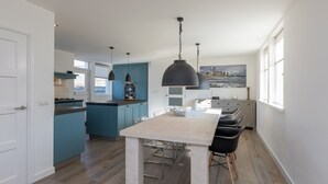 Una cucina moderna con isola centrale, illuminazione a sospensione e zona pranzo con sedie.