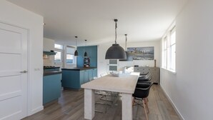 Una cucina moderna con isola centrale, illuminazione a sospensione e vista sulla città attraverso ampie finestre.