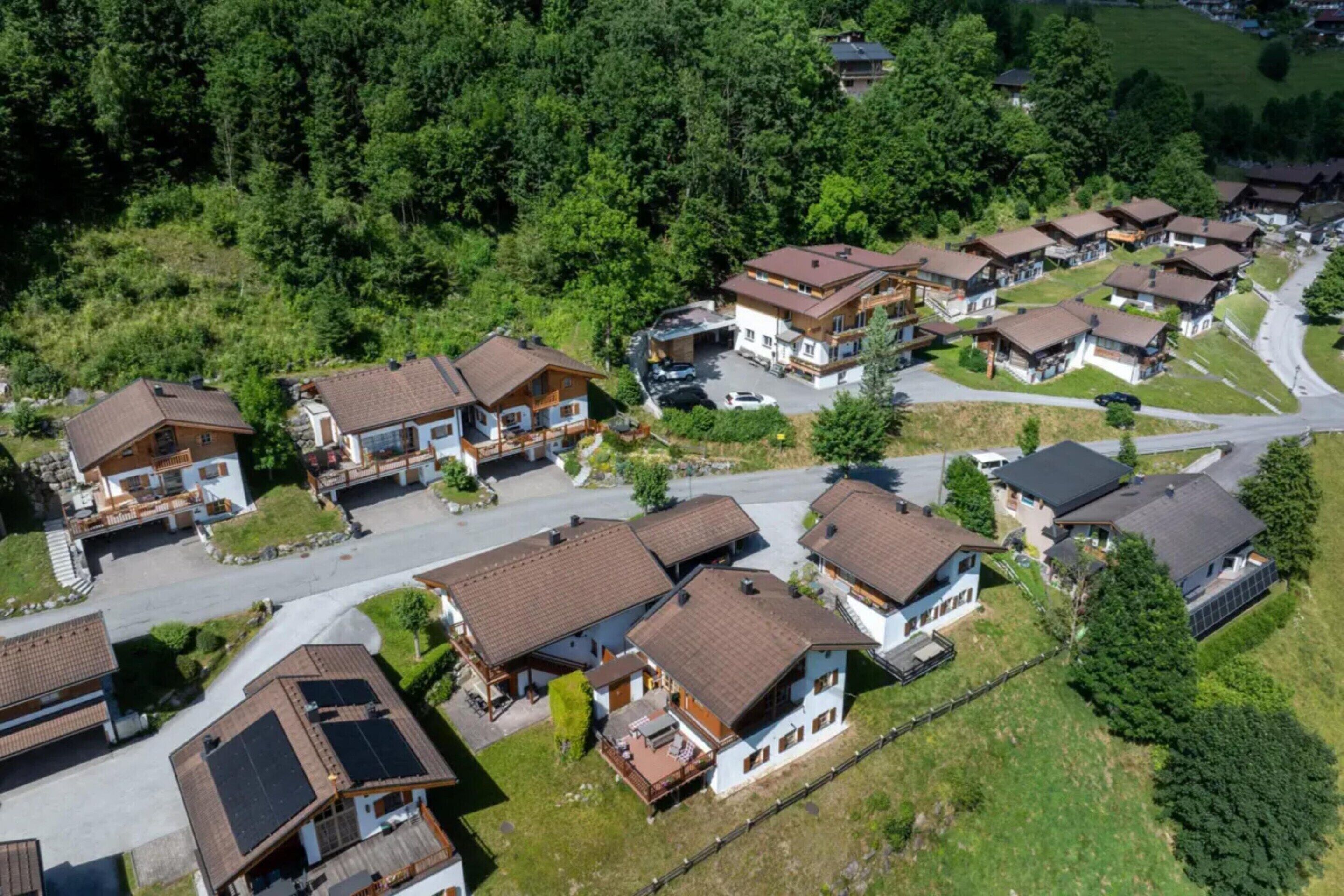 A residential area with multiple houses, each with a sloped roof and surrounded by greenery.