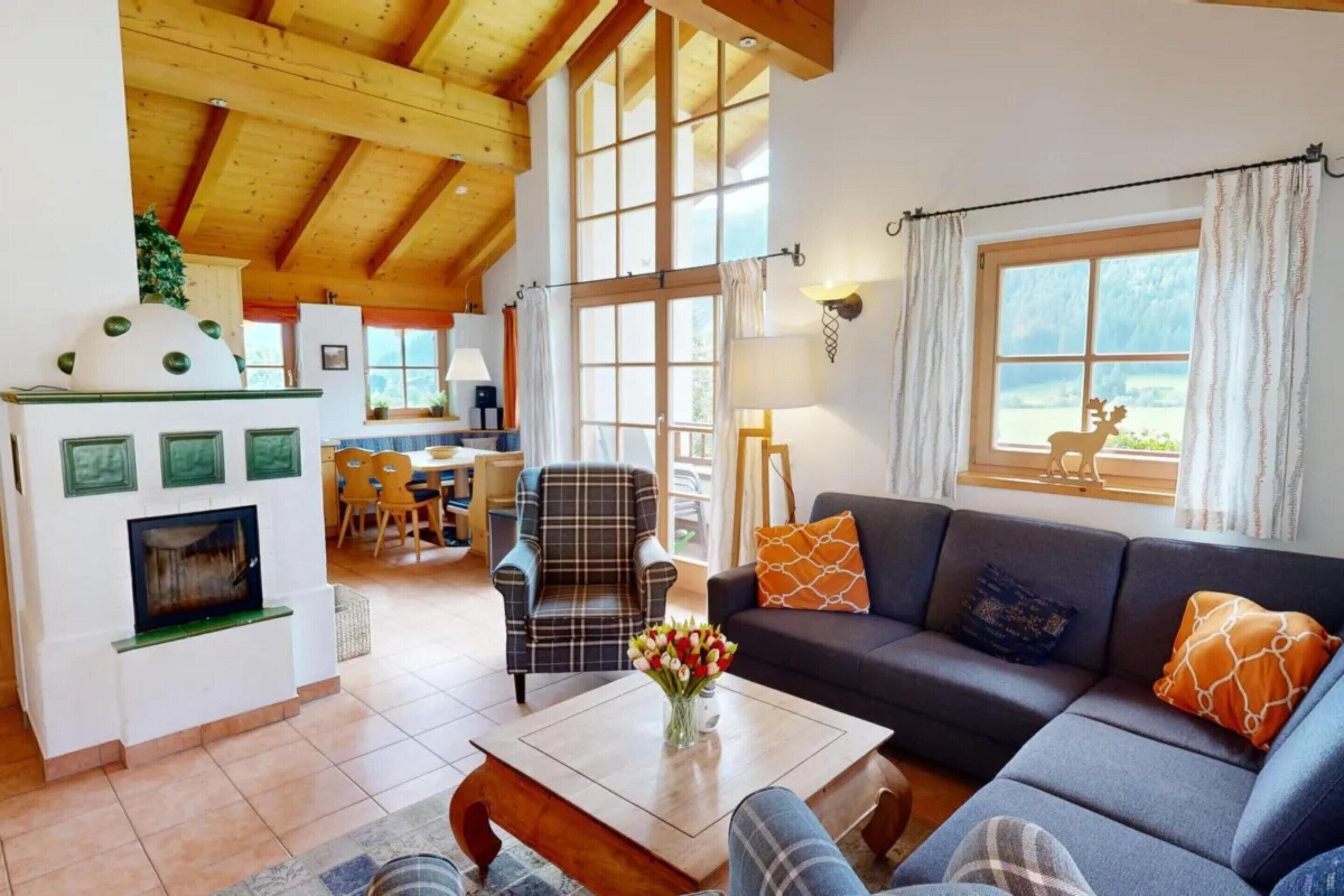 A spacious living area with a fireplace, a sofa, a dining table with chairs, and large windows providing natural light.