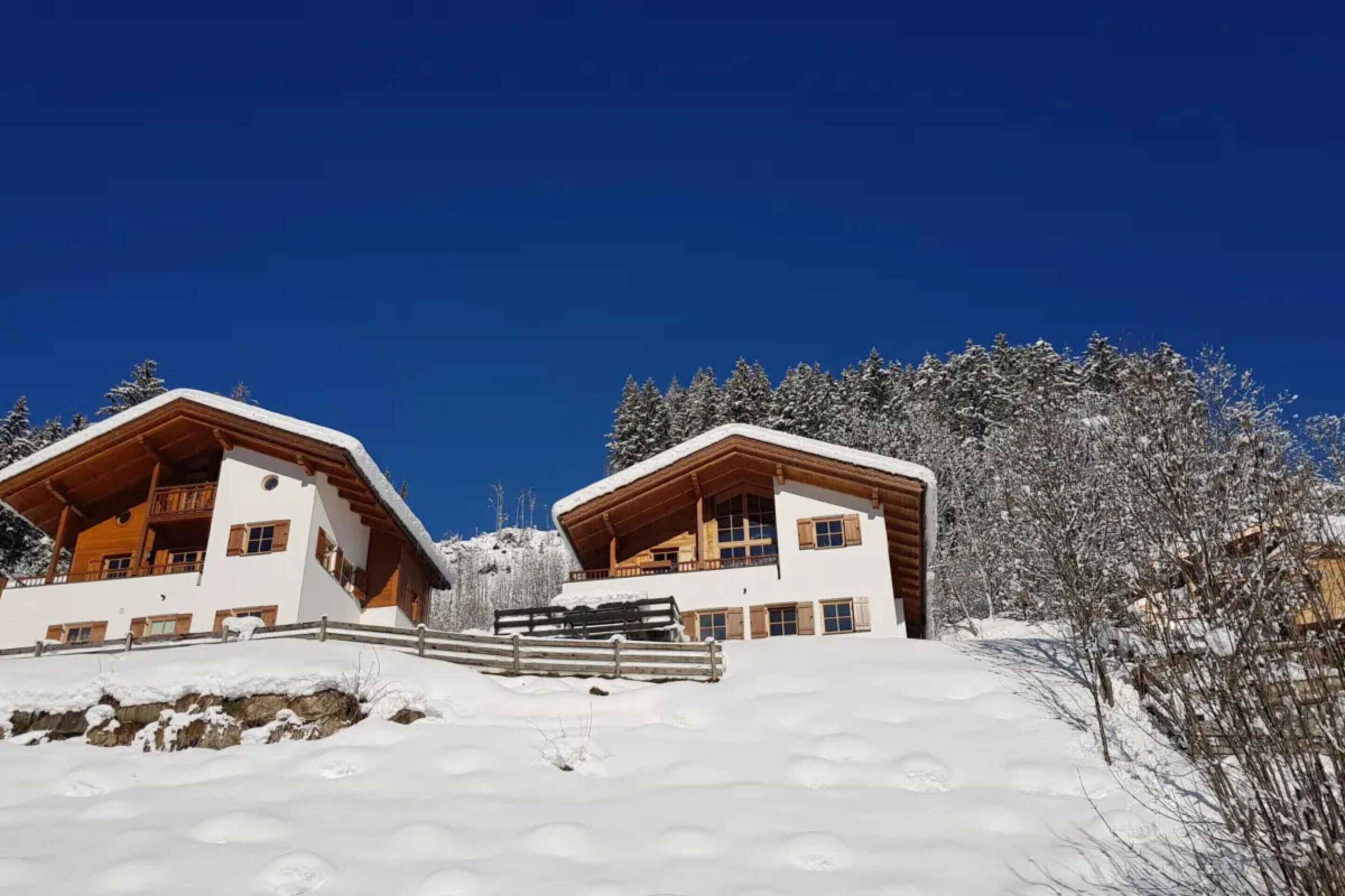 A snow-covered mountain lodge with a wooden facade and a clear blue sky.