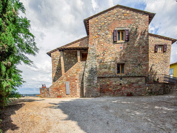 A stone building with a balcony, a small window, and a door.