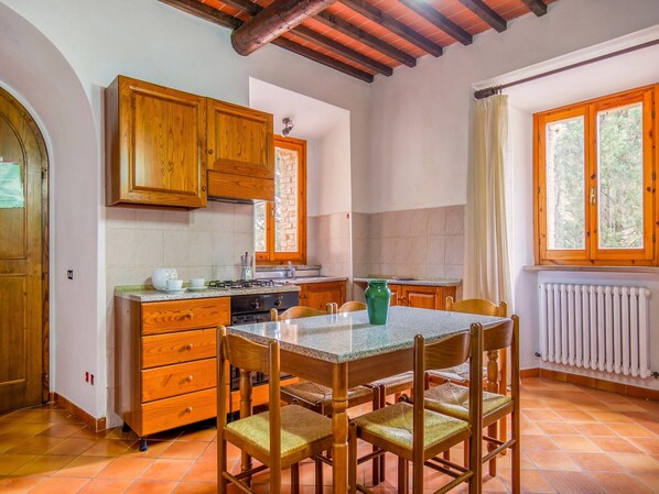 A kitchen with wooden cabinets, a granite countertop, and a dining table with chairs.