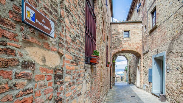 A narrow alleyway with a brick wall on the left and a stone building on the right. - Montaione Harmony: Lodging (Gambassi Terme)