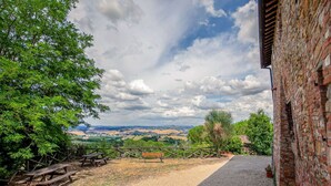 A rustic stone building with a gravel path leading to a wooden bench and picnic table. - Montaione Harmony: Lodging (Gambassi Terme)