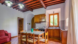 A cozy kitchen with wooden cabinets, a tiled floor, and a dining area with a table and chairs. - Montaione Harmony: Lodging (Gambassi Terme)