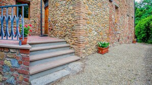 A stone building with a wooden door, a small porch with steps, and a gravel driveway. - Montaione Harmony: Lodging (Gambassi Terme)