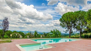 A rectangular swimming pool with a brick deck, surrounded by trees and a view of distant hills. - Montaione Harmony: Lodging (Gambassi Terme)