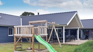 A wooden play structure with a slide in a backyard.