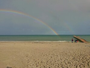 A beach with a rainbow, a pier, and a few people. - Holiday Home in Jerup (Jerup)