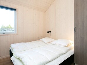 Habitación individual con techo y paredes de madera, una ventana y una lámpara de noche.
