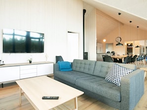 Uma sala de estar moderna com um sofá cinzento, uma mesa de centro e uma televisão de ecrã plano.