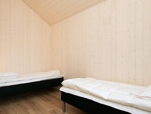 A room with two beds, wooden walls, and a sloped ceiling. - Holiday Home in Jerup (Jerup)