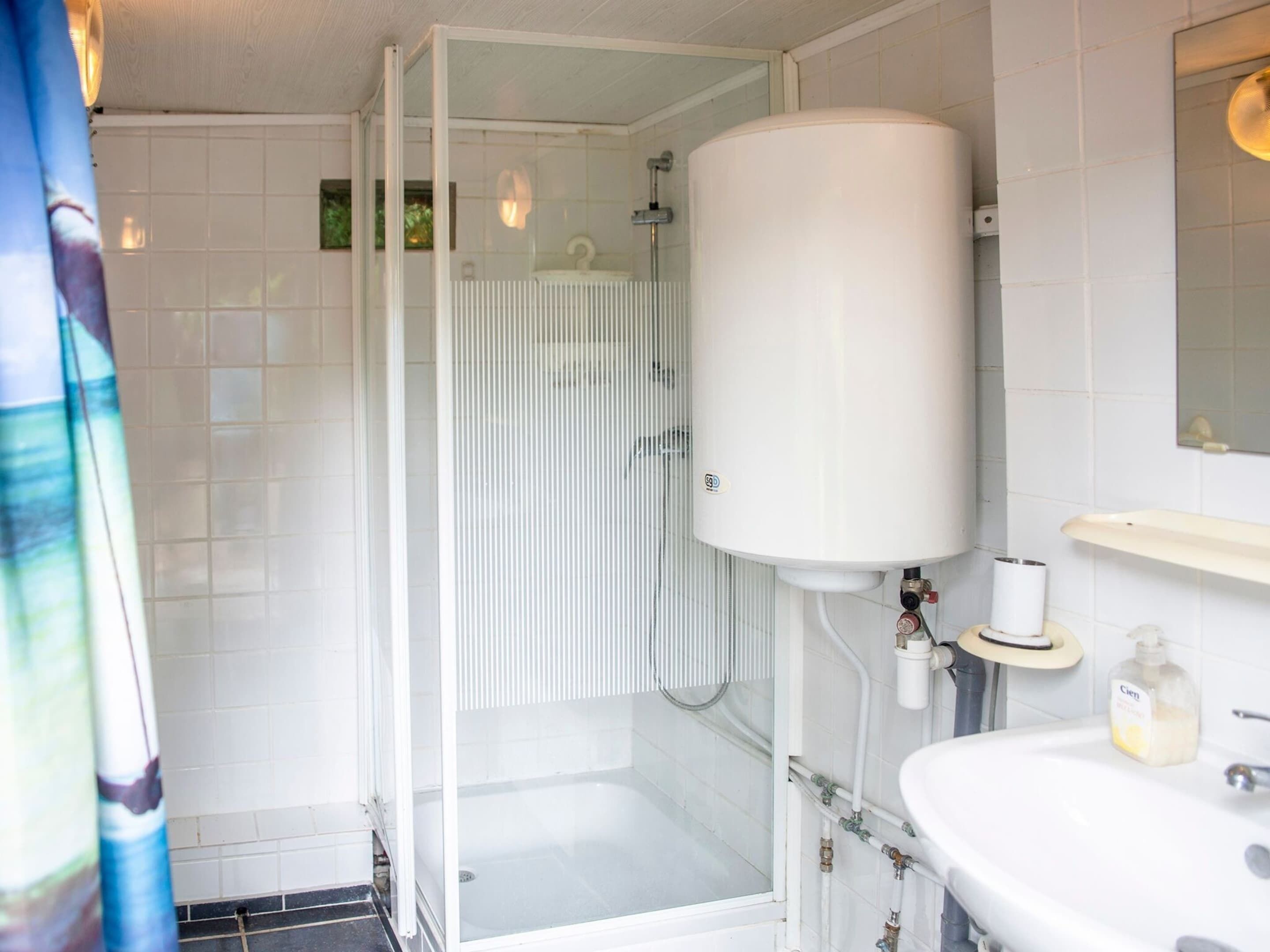 A bathroom with a glass shower enclosure, a white toilet, and a sink with a mirror above it.