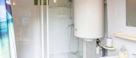 A bathroom with a glass shower enclosure, a white toilet, and a sink with a mirror above it.