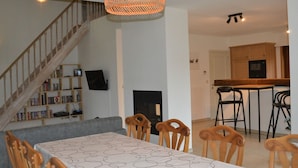 A dining area with a table and chairs, a staircase, a bookshelf, and a kitchen in the background. - Apartment in Antwerp Near Verbeke Museum (Sint-Niklaas)