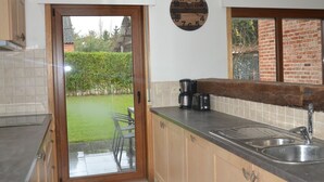 A kitchen with a sliding glass door leading to a garden, a coffee maker, and a toaster on the counter. - Apartment in Antwerp Near Verbeke Museum (Sint-Niklaas)