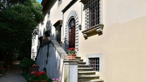 A building with a stone staircase leading to a door, surrounded by potted plants and a gravel path. - Rustic Elegance Near Florence (Rignano sull'Arno)