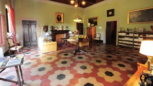 A spacious room with a hexagonal patterned floor, wooden ceiling beams, a fireplace, and a large painting on the wall. - Rustic Elegance Near Florence (Rignano sull'Arno)