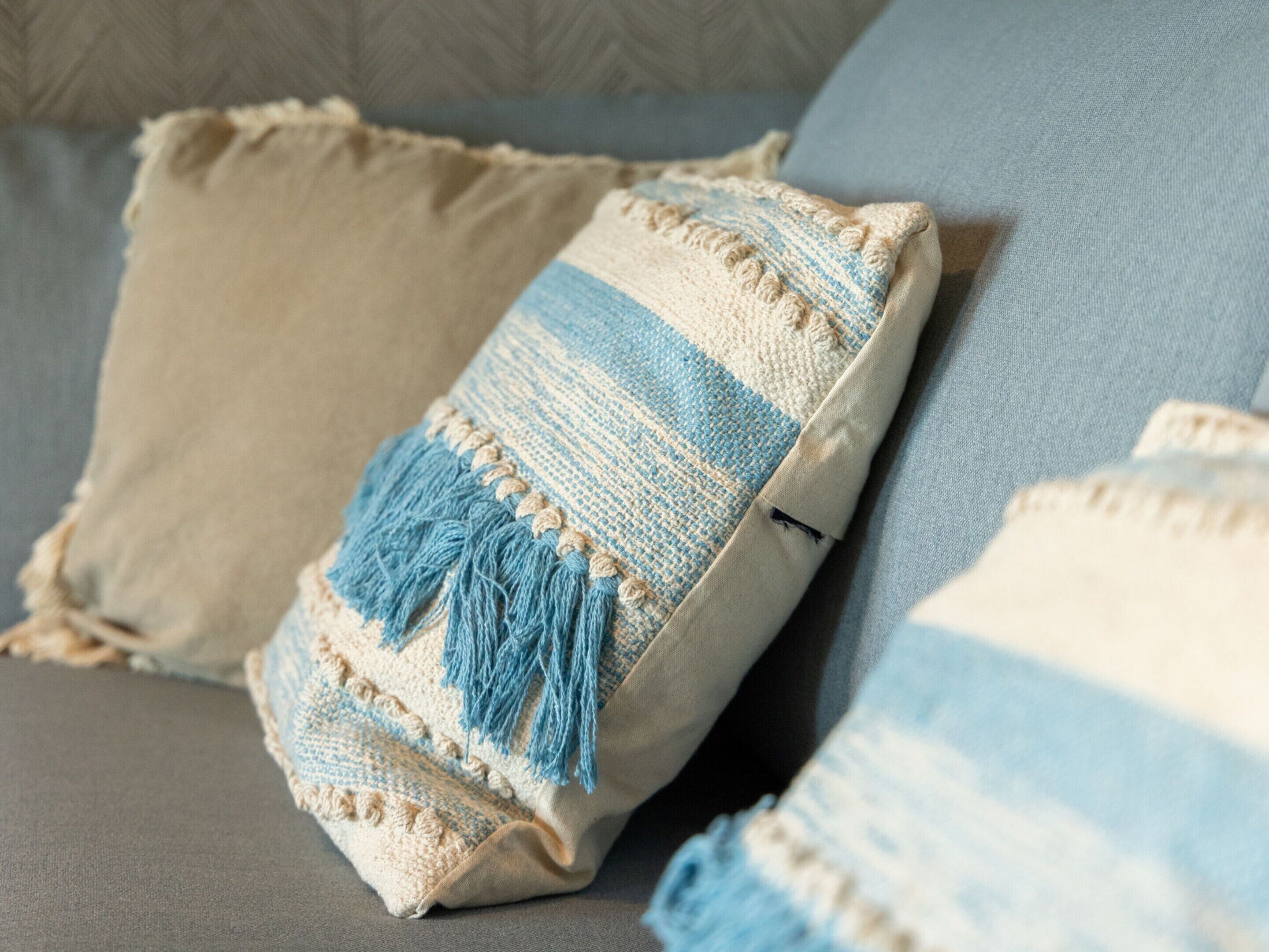 A close-up of a textured pillow with tassels on a couch.