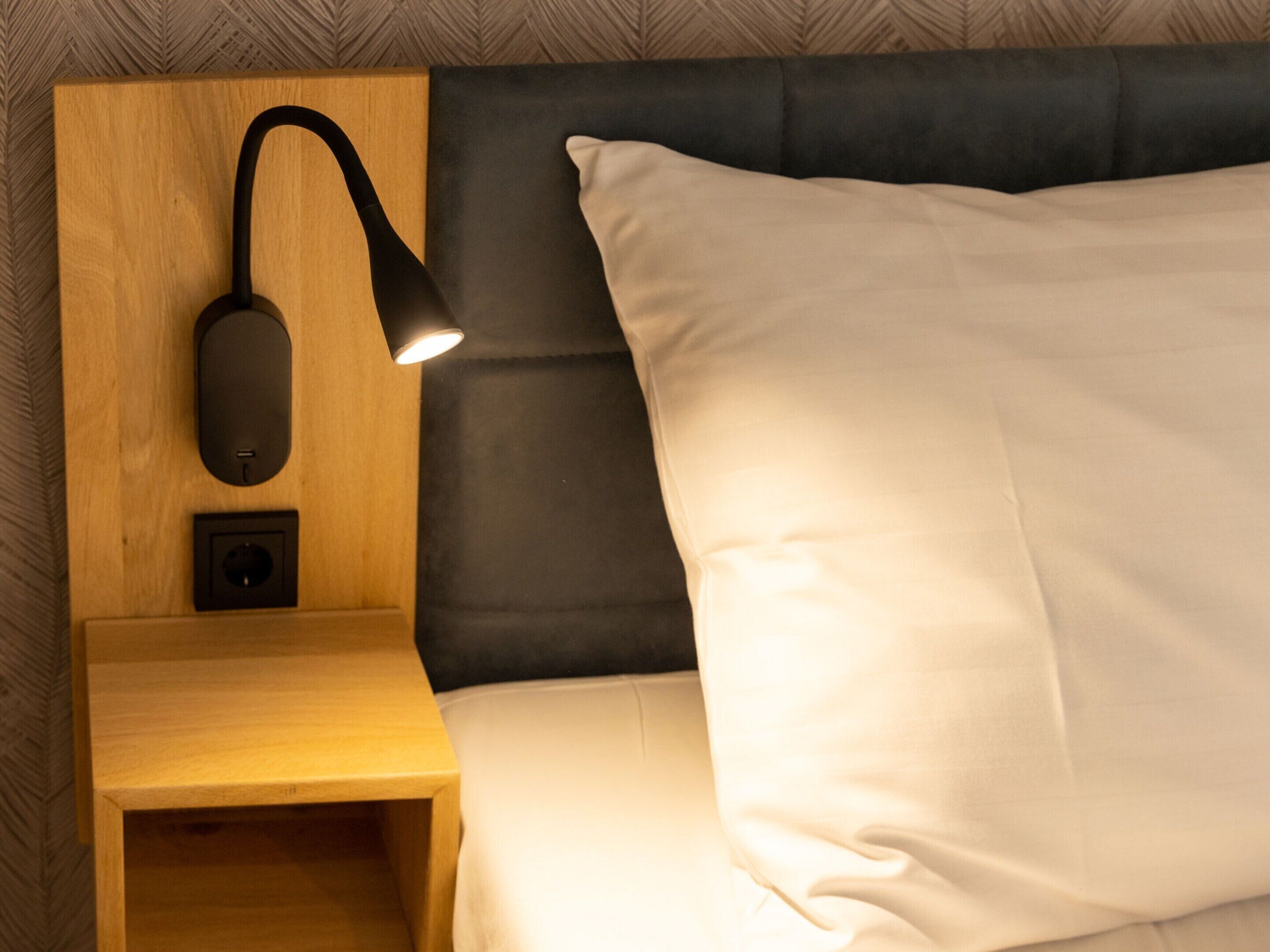 A neatly made bed with a white pillow and a black headboard.