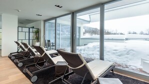 A modern indoor area with large windows, a seating area with chairs and tables, and a view of a snowy landscape outside. - Alluring Apartment in Höggen near Ski Slopes with Sauna (Radstadt)