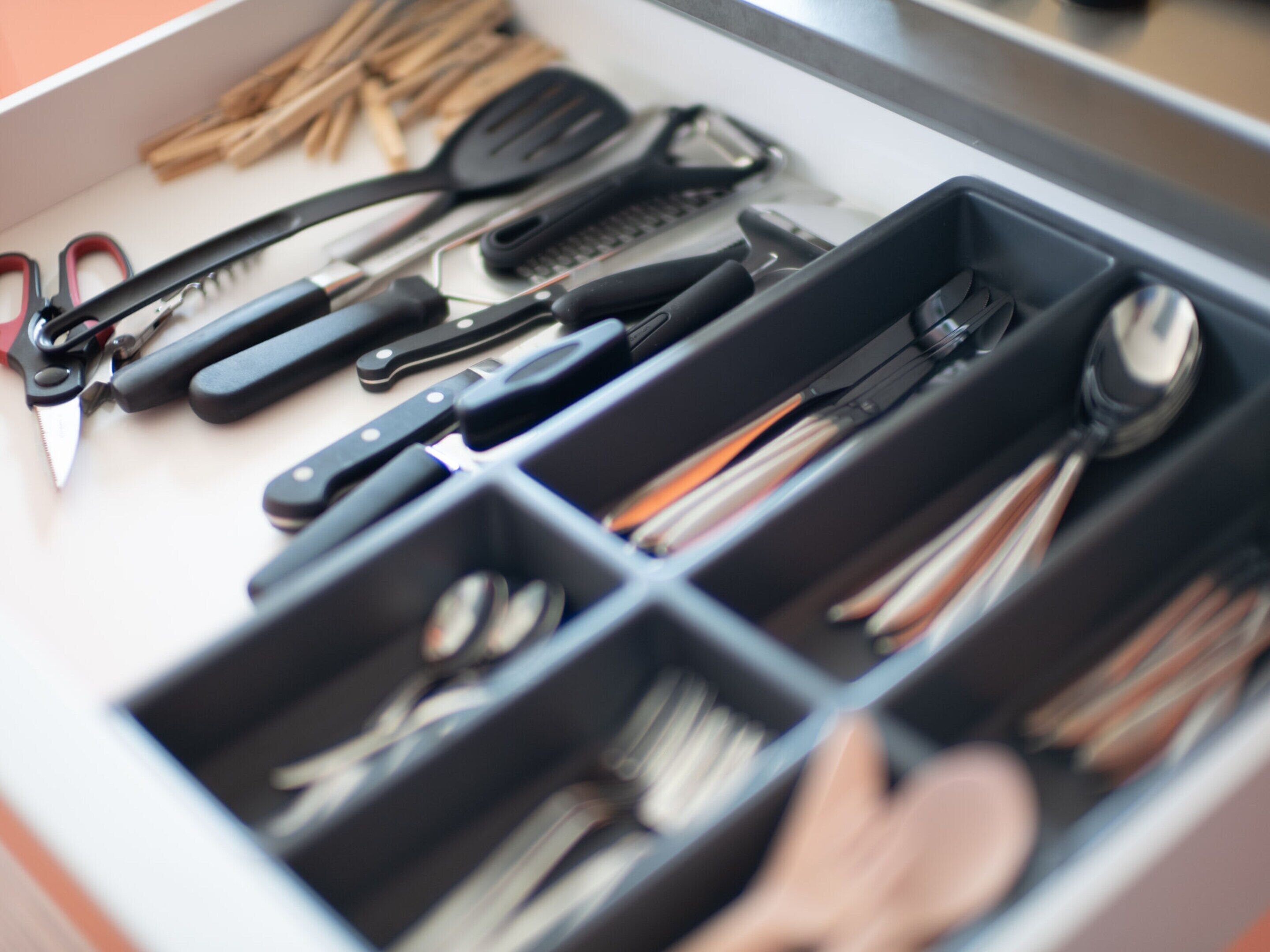Un cassetto contenente diversi utensili da cucina, disposti in scomparti.